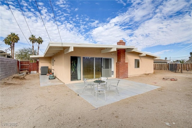 rear view of property featuring central air condition unit, a patio area, a fenced backyard, a chimney, and stucco siding