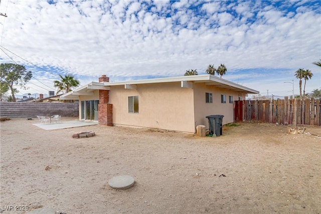 back of house with a chimney, fence, stucco siding, and a patio area