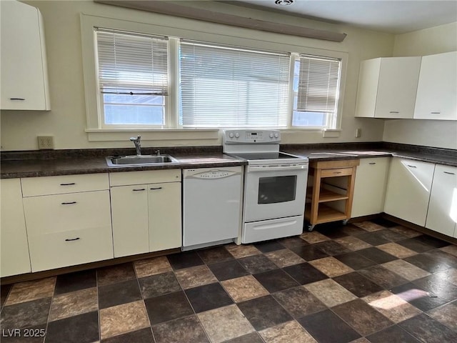 kitchen featuring dark countertops, white appliances, white cabinetry, and a sink