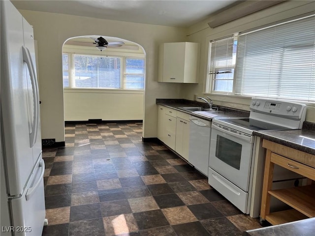 kitchen with white appliances, plenty of natural light, a sink, and baseboards