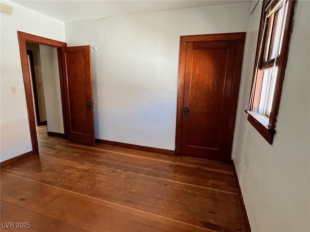 empty room featuring dark wood-style floors and baseboards