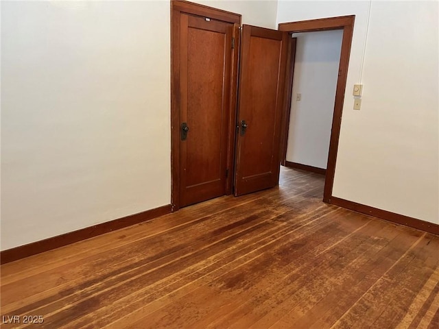 spare room with dark wood-type flooring and baseboards