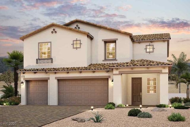 mediterranean / spanish-style house with a garage, decorative driveway, a tiled roof, and stucco siding