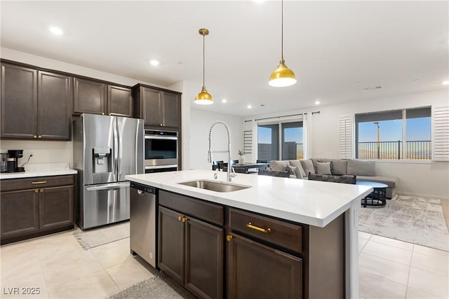 kitchen featuring stainless steel appliances, light countertops, a sink, and hanging light fixtures