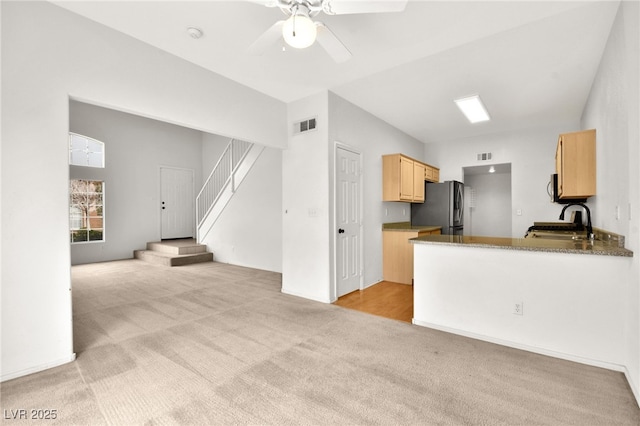 kitchen with visible vents, light colored carpet, stainless steel appliances, light brown cabinetry, and a sink