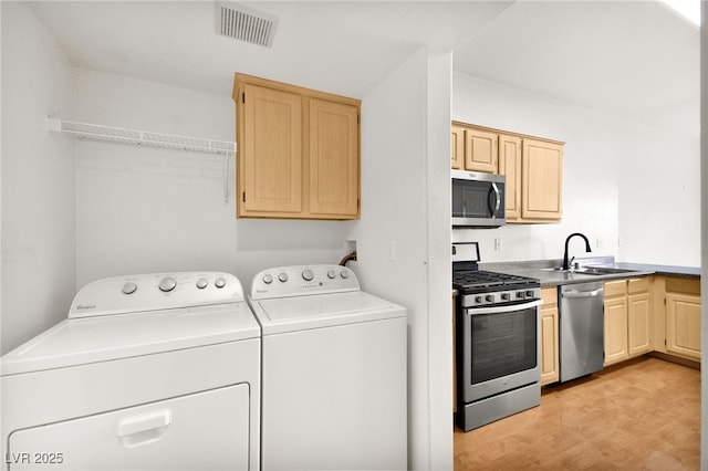 clothes washing area featuring laundry area, a sink, visible vents, washer and dryer, and light floors