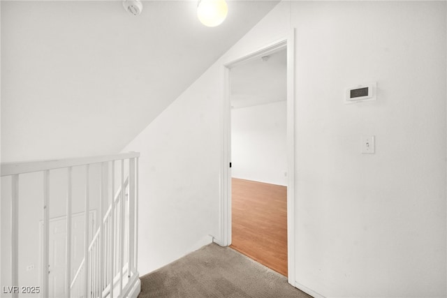 hall featuring light carpet, lofted ceiling, and an upstairs landing