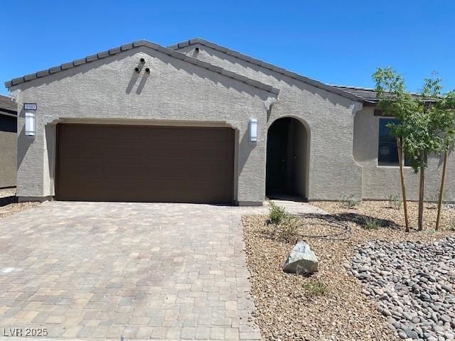 view of front of house featuring a garage, decorative driveway, and stucco siding