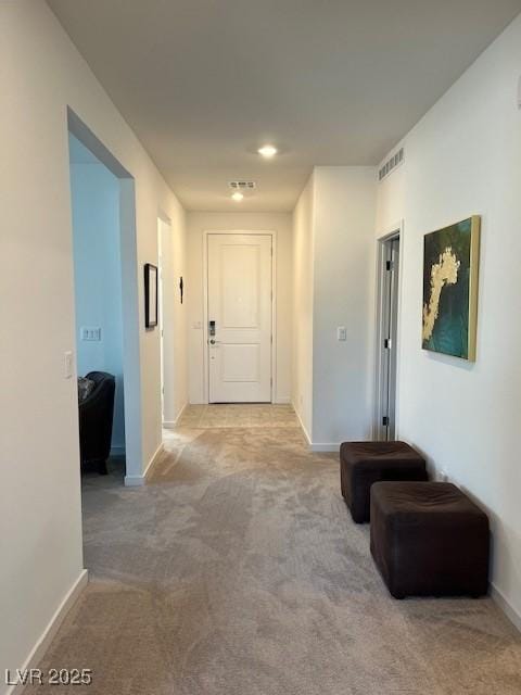 hall with light carpet, baseboards, and visible vents