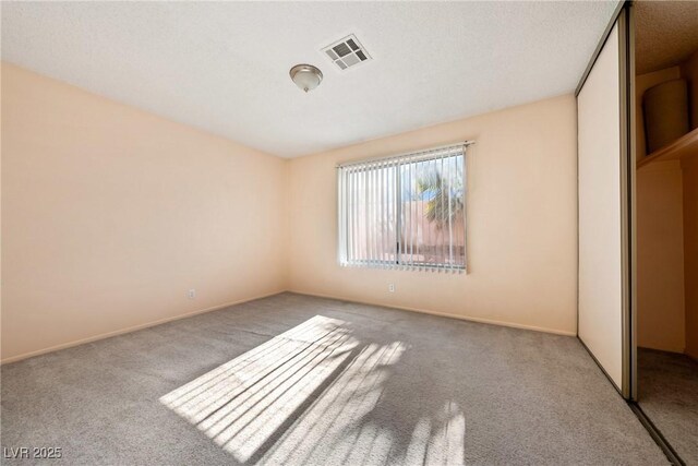 unfurnished bedroom featuring light carpet, visible vents, and a closet