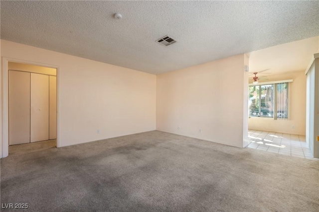 spare room featuring a textured ceiling, visible vents, and light colored carpet