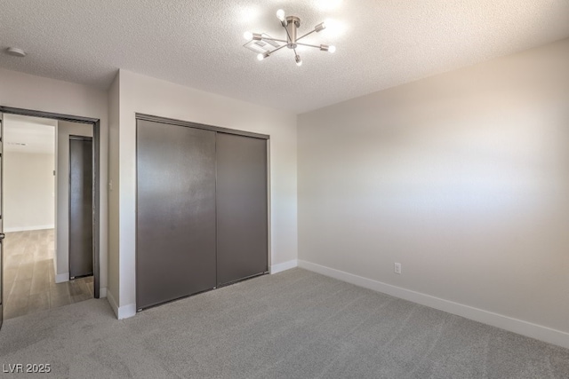 unfurnished bedroom with carpet, a closet, a textured ceiling, and baseboards