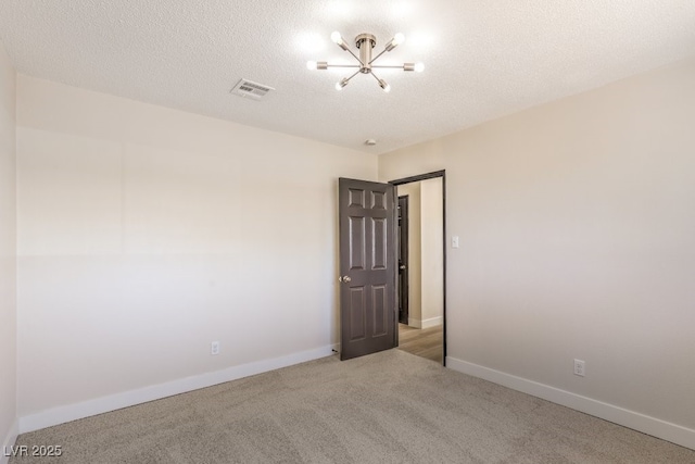 spare room with baseboards, a textured ceiling, visible vents, and carpet flooring