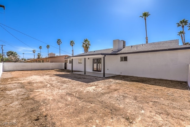 rear view of house with a patio area, fence, and stucco siding