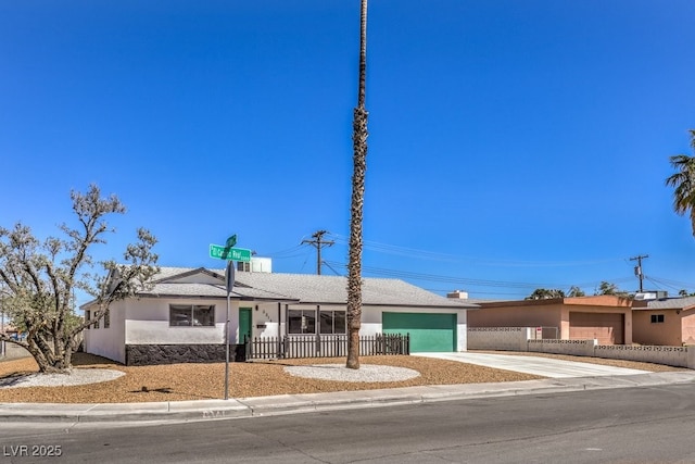 view of front of property with a garage, fence, concrete driveway, and stucco siding