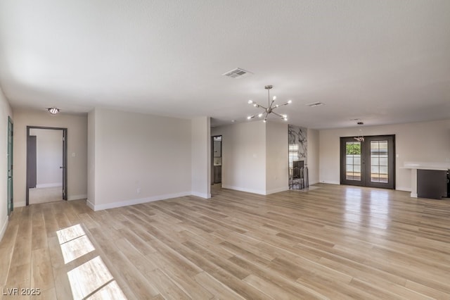 unfurnished living room featuring french doors, a notable chandelier, visible vents, light wood-style floors, and baseboards