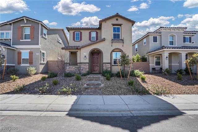 view of front of home featuring stucco siding, fence, a residential view, stone siding, and a tiled roof