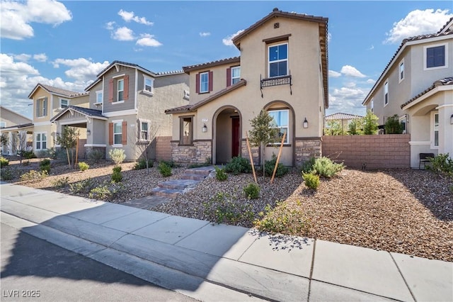 mediterranean / spanish-style home featuring stone siding, a residential view, fence, and stucco siding