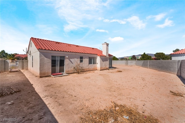 rear view of property with stucco siding, a fenced backyard, and a tiled roof