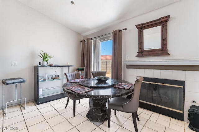 dining space featuring lofted ceiling, light tile patterned floors, and a fireplace