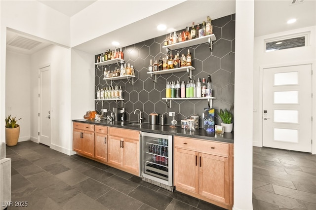 bar with wine cooler, a sink, baseboards, backsplash, and wet bar