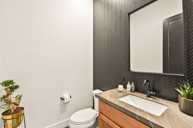 half bathroom featuring toilet, backsplash, vanity, and baseboards