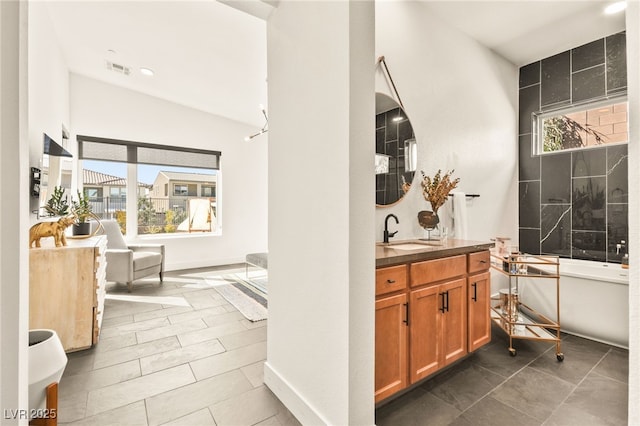 bathroom with a healthy amount of sunlight, baseboards, a freestanding bath, and vanity