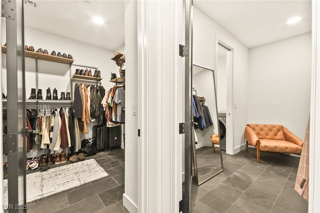 walk in closet featuring washer / clothes dryer and stone finish floor