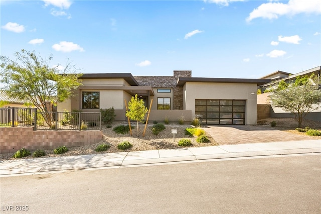 view of front of home featuring an attached garage, fence private yard, decorative driveway, and stucco siding