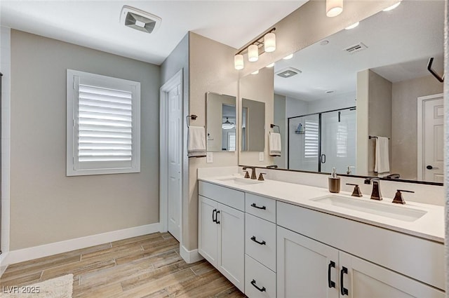bathroom with a shower stall, wood finished floors, baseboards, and a sink