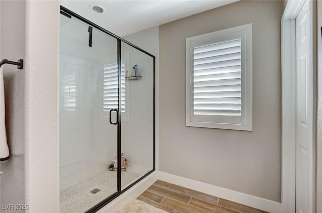 full bath with wood finish floors, baseboards, and a stall shower