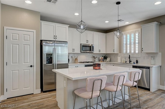 kitchen with a sink, visible vents, light wood-style floors, and appliances with stainless steel finishes
