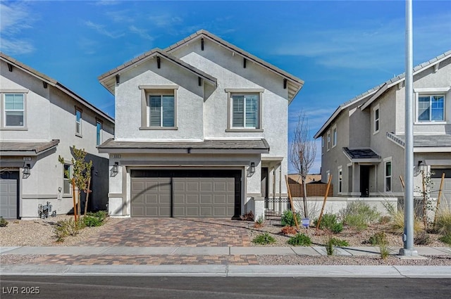 traditional-style home featuring a garage, decorative driveway, and stucco siding