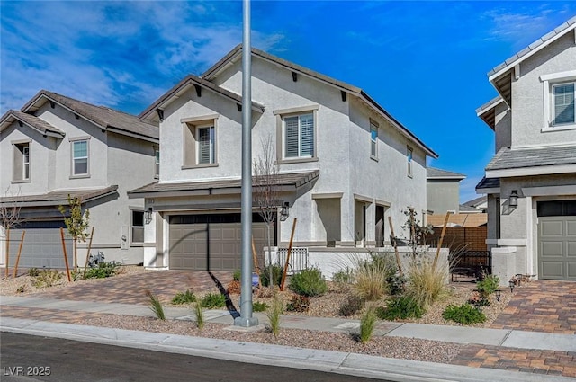 view of front of house featuring decorative driveway, fence, a garage, and stucco siding