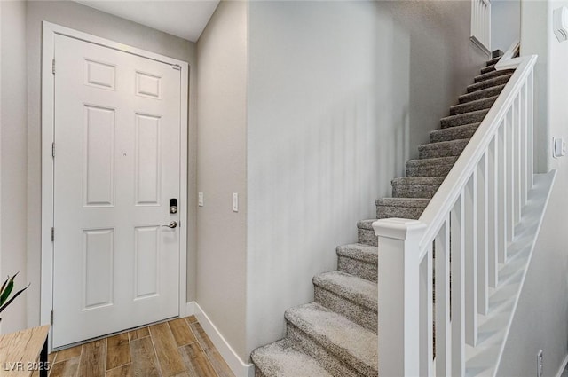 foyer entrance featuring stairway, baseboards, and wood finished floors