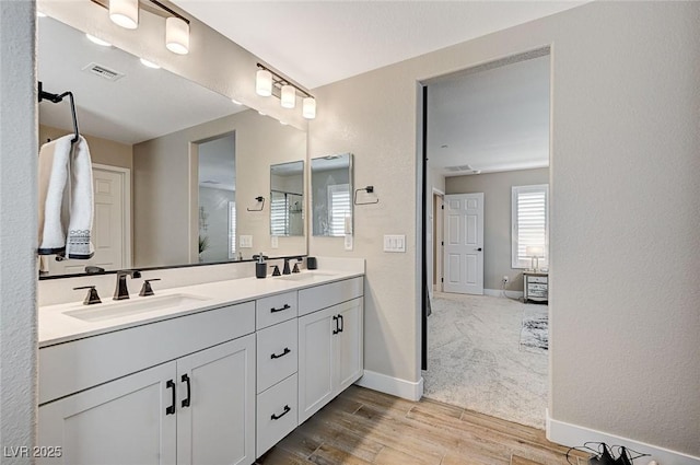 full bathroom with wood finished floors, baseboards, visible vents, double vanity, and a sink