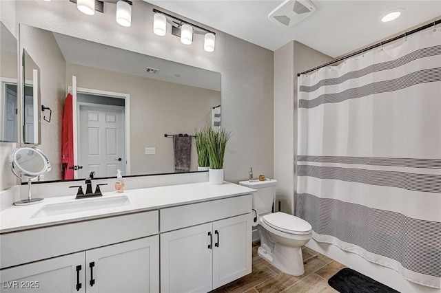 bathroom featuring visible vents, toilet, wood tiled floor, vanity, and a textured wall