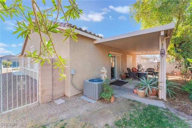 view of side of property with a tile roof, stucco siding, fence, and central air condition unit