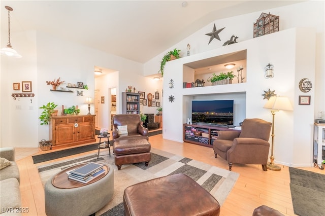 living area featuring built in shelves, light wood-style floors, and high vaulted ceiling