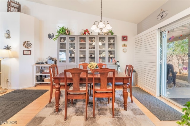 dining room featuring lofted ceiling, light wood finished floors, and an inviting chandelier