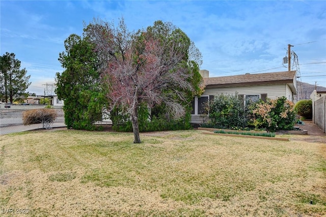 view of property hidden behind natural elements with a front lawn and fence