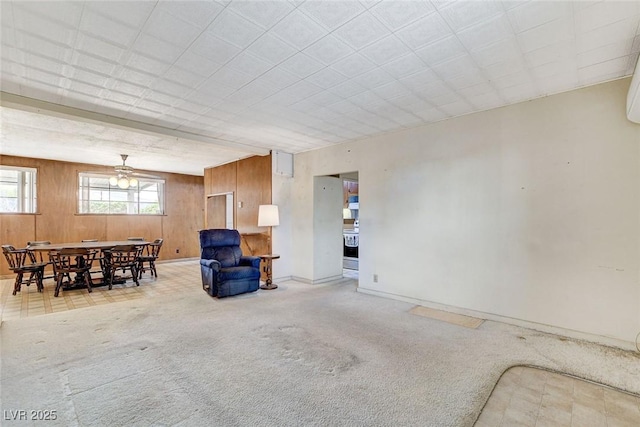 sitting room with light colored carpet, wooden walls, and baseboards