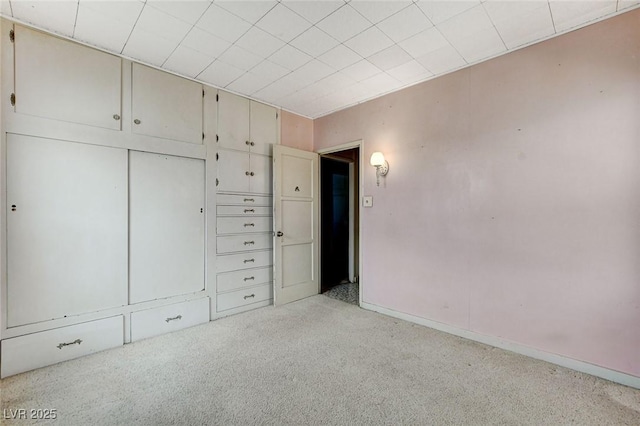 unfurnished bedroom featuring baseboards, a closet, and light colored carpet