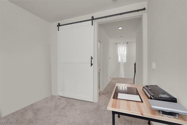 office space with a barn door and light colored carpet