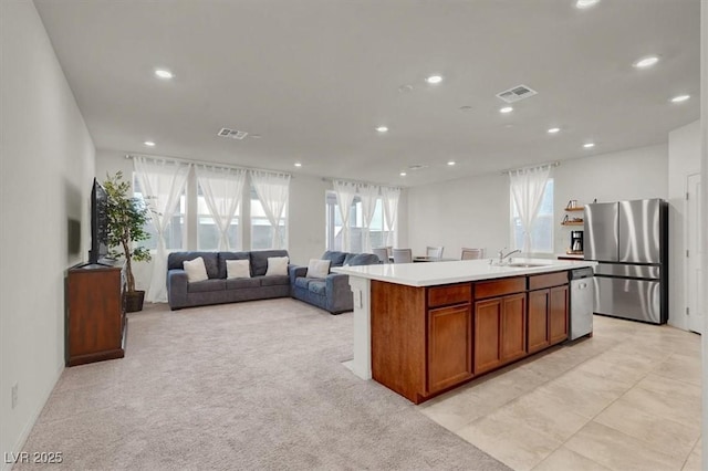 kitchen with a kitchen island with sink, visible vents, open floor plan, light countertops, and appliances with stainless steel finishes