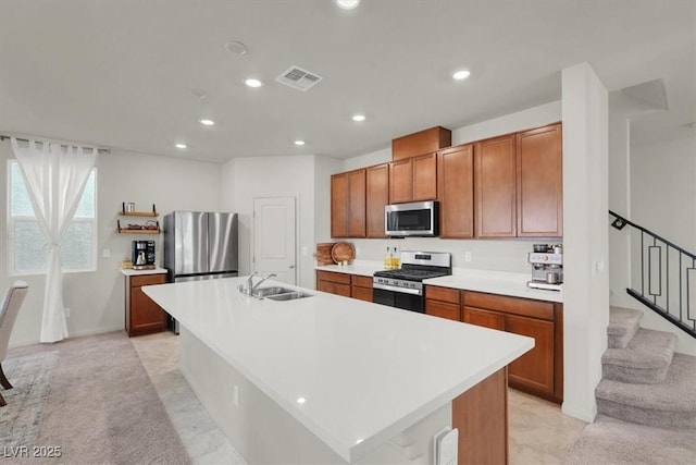 kitchen with stainless steel appliances, an island with sink, light countertops, and visible vents