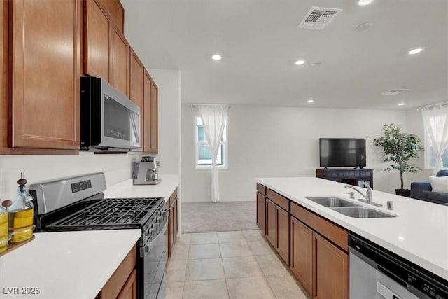 kitchen with stainless steel appliances, light countertops, visible vents, open floor plan, and a sink