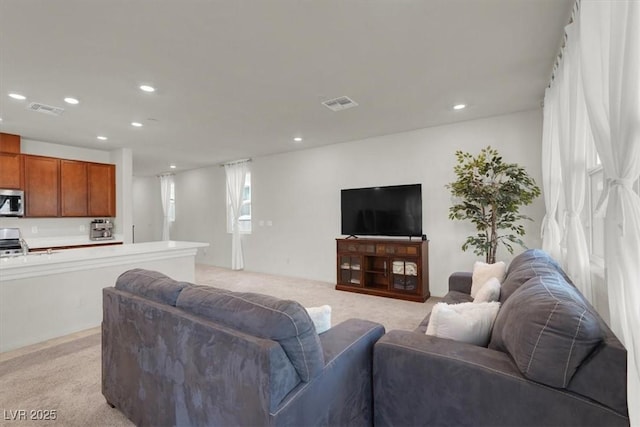 living room featuring recessed lighting, visible vents, and light colored carpet