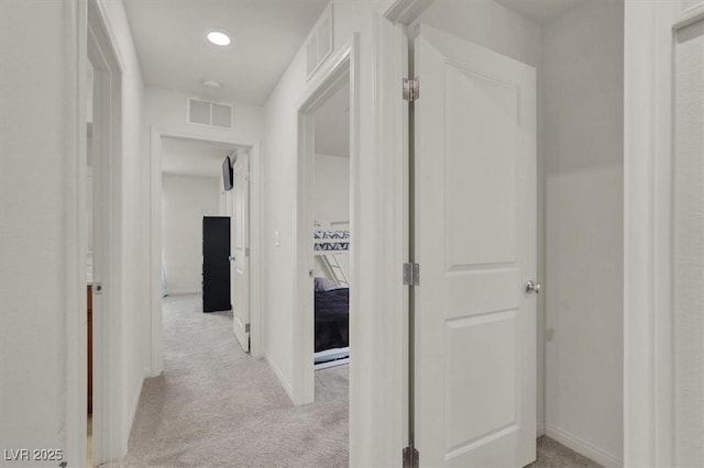 corridor with visible vents, light carpet, and baseboards