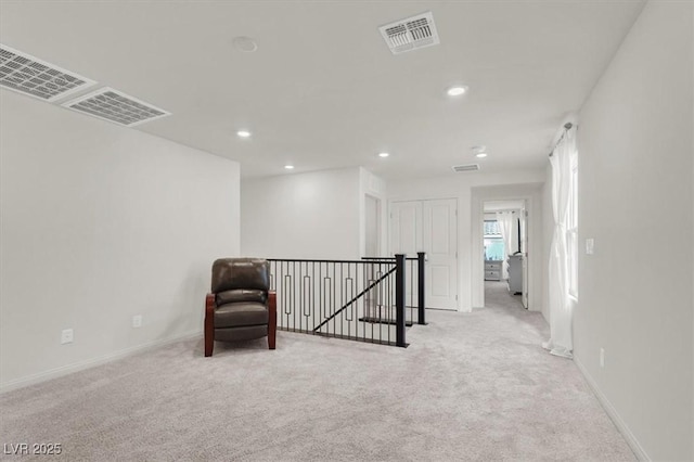 unfurnished room featuring light carpet, visible vents, baseboards, an upstairs landing, and recessed lighting